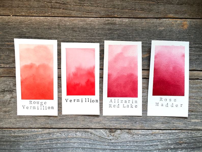 May include: Four watercolor paint swatches on white paper, labeled "Rouge Vermillion", "Vermillion", "Alizarin Red Lake", and "Rose Madder". The swatches show a gradient of red shades, from light to dark.