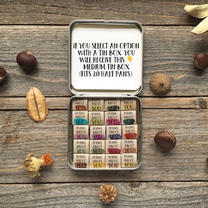 May include: A white tin box with the text "IF YOU SELECT AN OPTION WITH A TIN BOX, YOU WILL RECEIVE THIS MEDIUM TIN BOX (FITS 20 HALF PANS)." The box contains 20 small, colorful, wooden squares with the text "POEMS ABOUT YOU" on each.