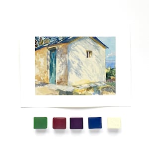 May include: A watercolor painting of a small building with a blue door and a white wall featuring tree shadow patterns. Below the painting are five square watercolor paint pans in green, maroon, purple, blue, and off-white colors.