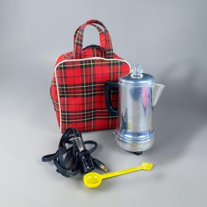 May include: A vintage chrome electric coffee percolator with a black handle and a clear glass top. Includes a red plaid carrying bag, a yellow plastic spoon, and a black power cord.