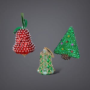 May include: Three beaded Christmas ornaments: a red bell, a green bell, and a green Christmas tree.