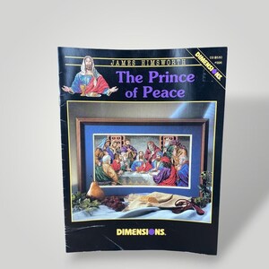 May include: A Dimensions cross-stitch kit titled "The Prince of Peace." The cover features an image of Jesus and a framed cross-stitch of a religious scene. The kit includes the text "JAMES HIMSWORTH" and "DIMENSIONS."