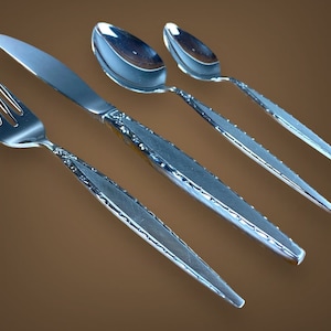 May include: A set of four silver-plated flatware pieces, including a fork, knife, and two spoons. The pieces have an ornate, textured design.