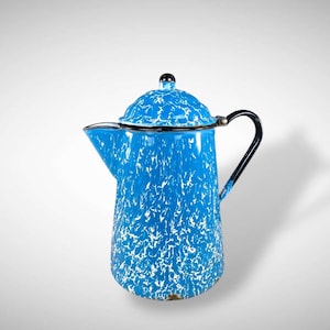 May include: Blue and white speckled enamelware coffee pot with a black handle and lid. The vintage-style pot has a spout for pouring and a black knob on the lid. A classic kitchenware item.