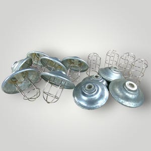 May include: A collection of galvanized metal industrial-style light fixtures. The set includes several dome-shaped shades with wire cages and matching circular bases. The metal has a silver-gray finish, and the design is reminiscent of vintage factory lighting.