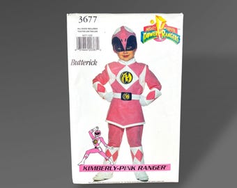 May include: A Butterick sewing pattern for a Kimberly Pink Ranger costume. The pattern features a child in a pink and white Power Rangers outfit with a black mask. The package includes the text "Mighty Morphin Power Rangers".