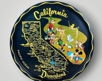 May include: A round black metal tray featuring a yellow map of California with city names and the Pacific Ocean labeled. The design includes illustrations of Goofy, Pinocchio, Bambi, Tinker Bell, Jiminy Cricket, Donald Duck, and Mickey Mouse.