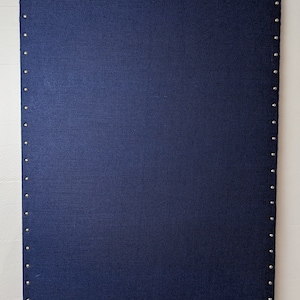 May include: A rectangular navy blue fabric panel with a textured surface. The edges are lined with evenly spaced silver-colored studs. The panel is displayed against a white background.