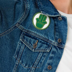 Hamsa embroidered iron on patch with Hebrew word prosperity. Round sew on green applique