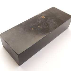 May include: A rectangular, dark brown wooden box with a slightly distressed surface. The box has a simple, minimalist design and appears to be made of solid wood. The box is likely used for storage or display.