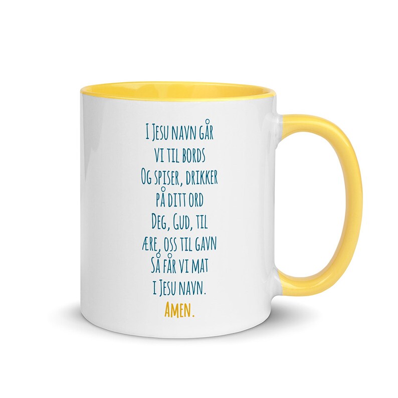K&ouml;nnte beinhalten: Eine wei&szlig;e Keramiktasse mit gelbem Rand. Die Tasse zeigt ein blaues Textdesign mit der Aufschrift "I JESU NAVN G&Aring;R VI TIL BORDS OG SPISER, DRIKKER P&Aring; DITT ORD DEG, GUD, TIL &AElig;RE, OSS TIL GAVN S&Aring; F&Aring;R VI MAT I JESU NAVN. AMEN."
