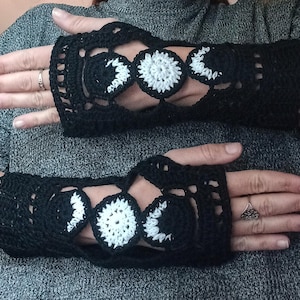 Puede incluir: Guantes sin dedos de crochet negro con un diseño de fases lunares. Los guantes tienen una base negra con detalles de fases lunares blancos y negros. El diseño calado ofrece flexibilidad, lo que los convierte en un accesorio elegante.