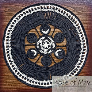 May include: Black and white crocheted mandala with a geometric design. The mandala is round and has a fringe border.