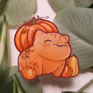 Könnte beinhalten: Eine orangefarbene Comicfigur mit einem Kürbis auf dem Kopf und Kürbissen drumherum. Die Figur hat ein breites Lächeln und trägt einen Kürbis-Hut.