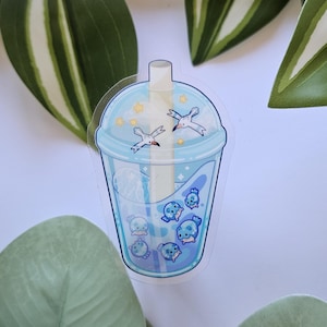 Op de afbeelding: Een heldere sticker met een blauw bubble tea-ontwerp. De bubble tea-beker heeft een lichtblauw deksel met twee zeemeeuwen en sterren. De beker is gevuld met blauwe vloeistof en cartoonzeehonden.