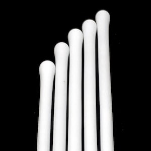 May include: Five white glass stirring sticks with rounded ends. The sticks are arranged in a fan shape, with the longest stick at the top and the shortest stick at the bottom.