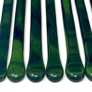 May include: Ten green and black glass rods with rounded ends. The rods have a marbled appearance.