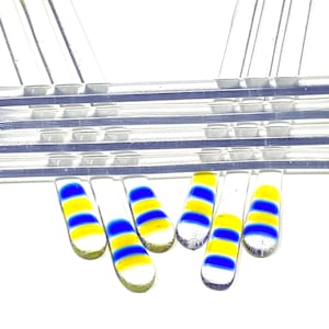 May include: A set of eight clear glass stirring sticks with blue and yellow stripes. The sticks are arranged in a fan shape.