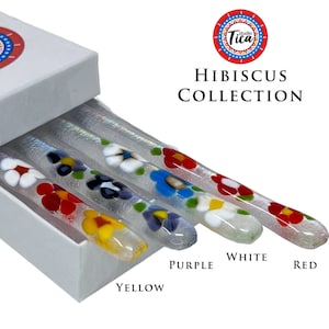 May include: Set of four glass stirring sticks with colorful hibiscus flower designs. The sticks are in a white box with the words "Hibiscus Collection" printed on the box. The colors of the sticks are yellow, purple, white, and red.