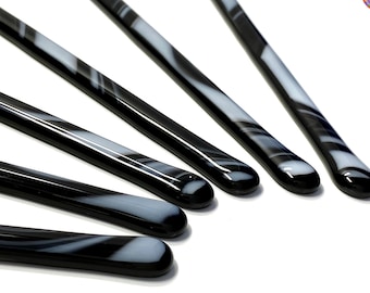 May include: Five black and white glass stirring sticks with rounded ends. The sticks have a marbled pattern.