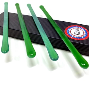 May include: Four green glass stirring sticks in a black box with a colourful logo that says "Studio Tica".