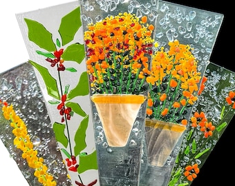 May include: A collection of four fan-shaped fused glass panels featuring botanical designs. The panels display yellow flowers, green holly leaves with red berries, and orange floral arrangements in pots, all accented with clear glass textures.