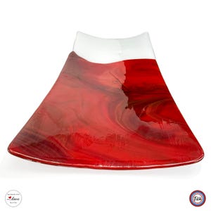 K&ouml;nnte beinhalten: Eine trapezf&ouml;rmige Glasschale mit einer glatten, gl&auml;nzenden Oberfl&auml;che, einem tiefroten Marmormuster und einem durchgehenden wei&szlig;en Band am oberen Rand. Die Schale hat geschwungene Seiten und eine breite, leicht gew&ouml;lbte Basis.