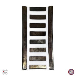 Overhead view of a rectangular fused glass tray with a white center stripe crossed by horizontal dark metallic brown bars.