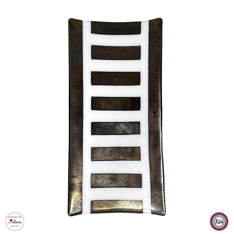 Overhead view of a rectangular fused glass tray with a white center stripe crossed by horizontal dark metallic brown bars.