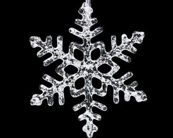May include: A silver snowflake ornament with a glittery finish. The snowflake has six points and is designed to hang from a string.