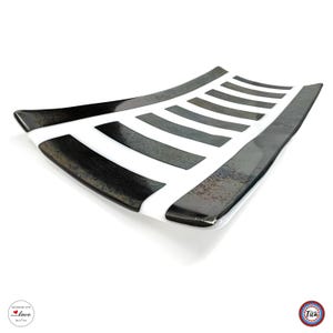 An angled view of a rectangular curved glass tray with a white base and dark, textured vertical stripes.