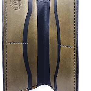 May include: Open view of a handmade leather card holder. The interior features a dark olive green and black color scheme with a central black stripe. The edges are stitched with black thread. The maker's mark is stamped on the inside.