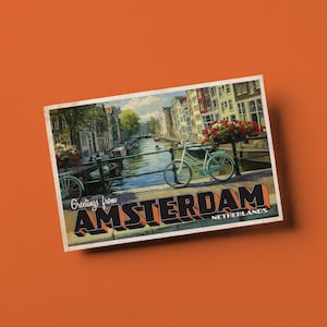 May include: A vintage postcard featuring a canal scene in Amsterdam, Netherlands. The image shows a light blue bicycle on a bridge, with buildings and boats along the canal. The postcard has the text "Greetings from Amsterdam" in a bold, retro font.