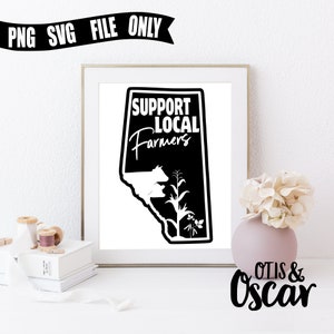 Op de afbeelding: Zwart-wit grafisch ontwerp van een staatsschets met de tekst "Support Local Farmers" erin. De grafiek wordt weergegeven in een wit frame op een wit oppervlak.