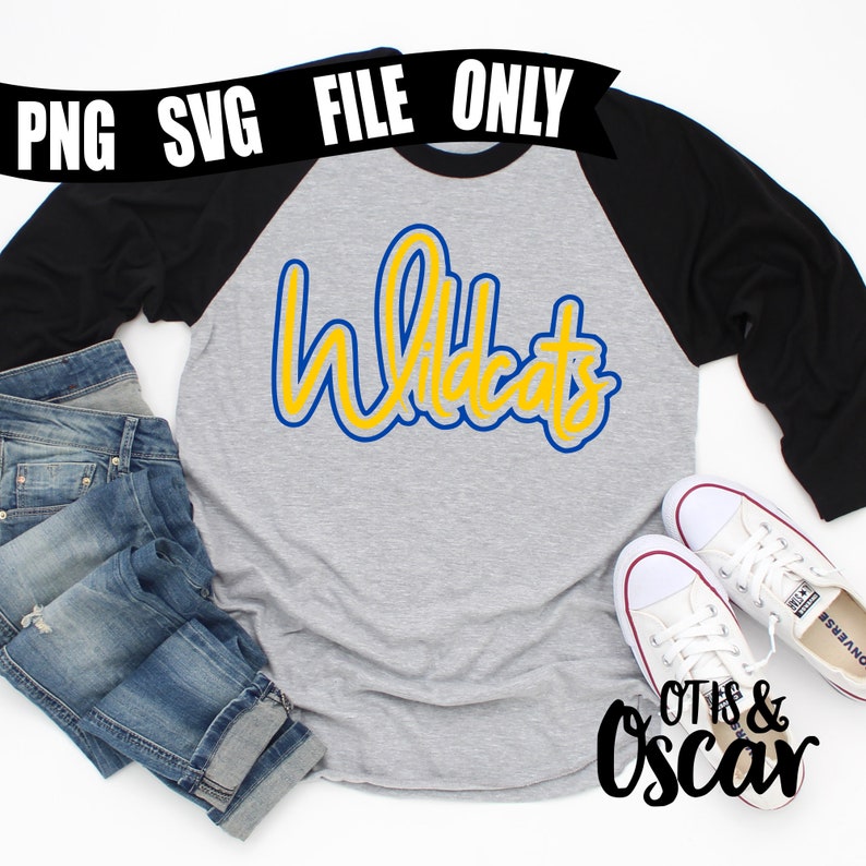 May include: A gray and black baseball tee shirt with the word "Wildcats" in yellow and blue lettering. The shirt is laying on a white surface with a pair of white sneakers and a pair of blue jeans.