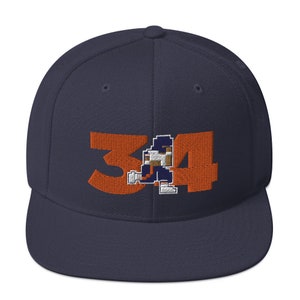 May include: A navy blue baseball cap with an orange embroidered number 34 and a pixelated football player design.