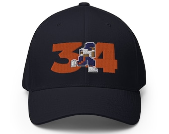Könnte beinhalten: Eine marineblaue Baseballkappe mit einer orangefarbenen gestickten Nummer "34" und einem pixelartigen Fußballspieler in der Mitte.