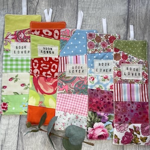 May include: Five colorful fabric bookmarks with the text "Book Lover" on each. The bookmarks are made of patchwork fabric with different patterns and colors, including floral, polka dot, and plaid.