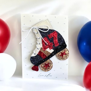 May include: A white card with a black, red and gold glitter roller skate with the number "47" on it. The card has a white string tied around it and the text "Linen + Boo" is printed on the bottom.