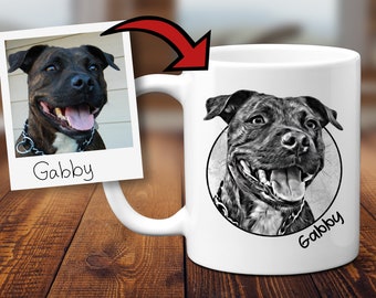 May include: White ceramic mug with a black and white illustration of a dog's face. The dog is smiling with its tongue out. The dog's name, "Gabby", is written below the illustration.