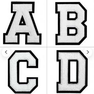 May include: Four white felt letters with black outlines. The letters are A, B, C, and D. The letters are in a blocky, uppercase font.