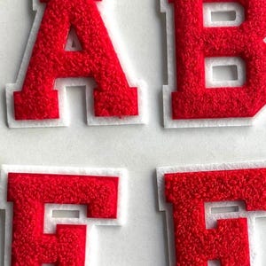 May include: Red felt letters A, B, E, and F with white outlines. The letters are raised and have a fuzzy texture.