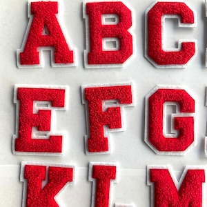 May include: Red felt letters of the alphabet, A, B, C, E, F, G, K, L, and M. The letters are outlined in white.