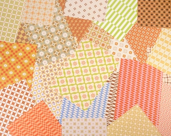 Op de afbeelding: Een verzameling rechthoekige vellen papier met diverse herhalende geometrische en florale patronen in tinten oranje, geel, groen, blauw en bruin. De ontwerpen bevatten rasters, sterren, golvende lijnen en kleine bloemmotieven.