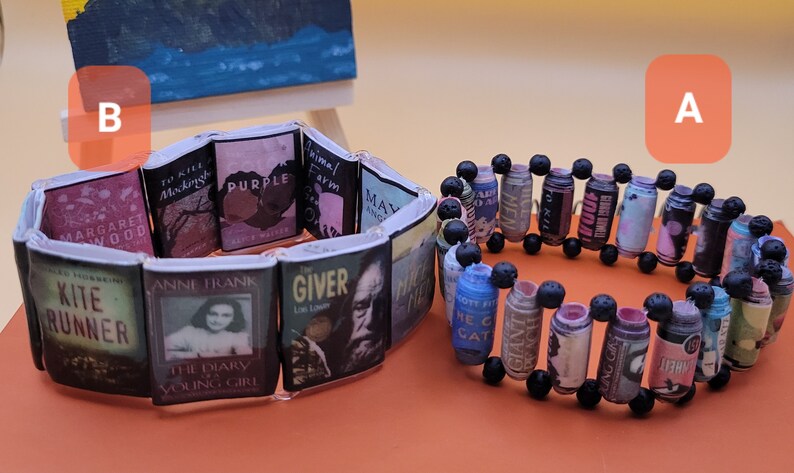 May include: Two book-themed bracelets. One bracelet is made with small book covers and the other is made with rolled-up pages of books and black beads.