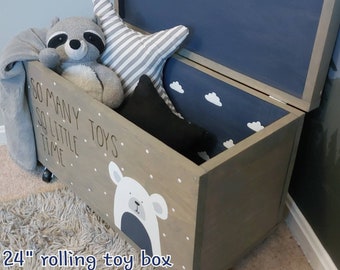 May include: A 24-inch wooden toy box with wheels, painted gray with white polka dots. The lid is open and features a blue interior with white clouds. The box is decorated with a white polar bear and the text "So many, so little toys, time".
