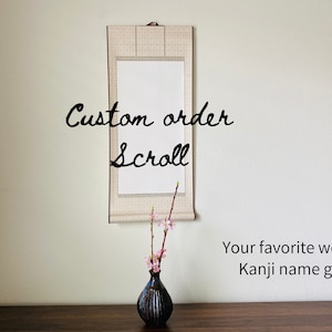 May include: A custom scroll with the words "Custom order Scroll" in a handwritten font. The scroll hangs on a wall above a dark vase with pink flowers. Text below reads "Your favourite word, Kanji name gift."