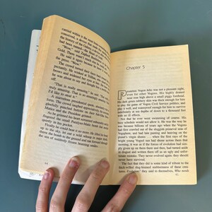 May include: An open book with aged pages, displaying printed text and the heading "Chapter 5." The book is angled, showing the page edges. The text is in black.