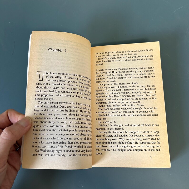 May include: An open book with text on aged pages. The text is divided into chapters, with the first chapter titled "Chapter 1". The text describes a house and the events of a Thursday morning.