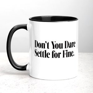 May include: White ceramic coffee mug with a black rim and handle. The mug has the text "Don't You Dare Settle for Fine." printed in black.